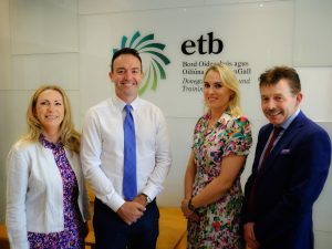 Four people standing side by side in front of Donegal ETB's logo on a wall.