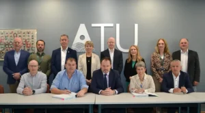 Group of peole - a row sitting behind a table and a row behind. 