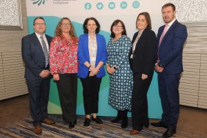 Six people standing in front of a banner