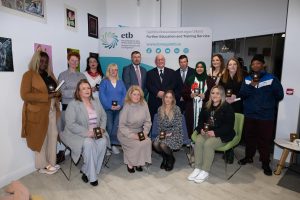 Group of people sitting and standing, some holding awards. 