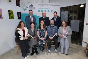 Group of people sitting and standing, some holding awards.