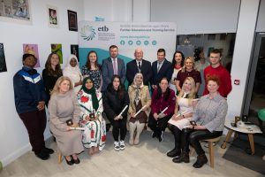 Group of people sitting and standing, some holding awards.