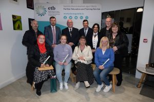 Group of people sitting and standing, some holding awards.