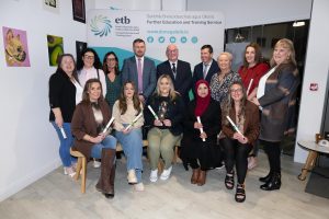 Group of people sitting and standing, some holding awards.