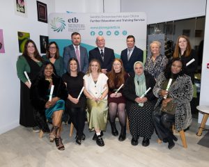 Group of people sitting and standing, some holding awards.